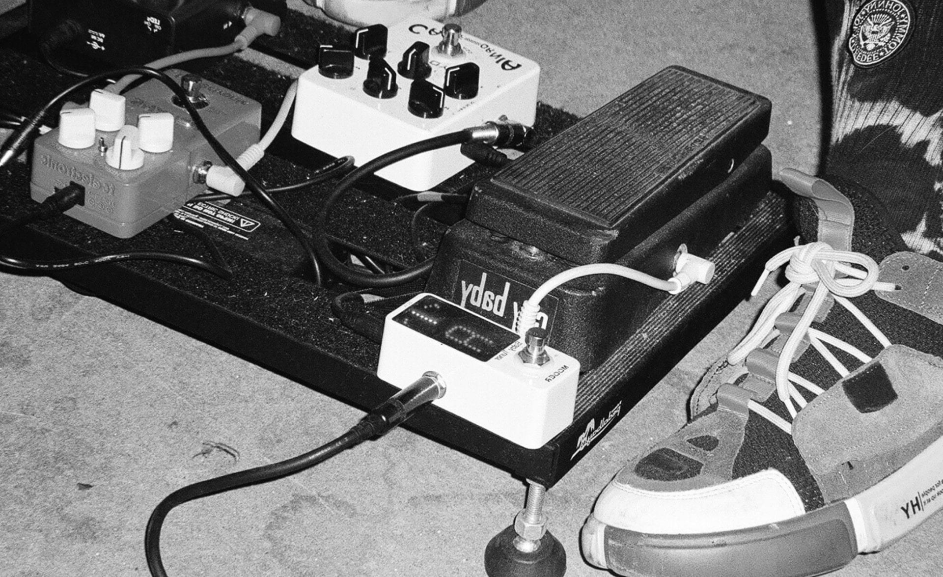 A black and white photo of a person's feet next to an electronic device.
