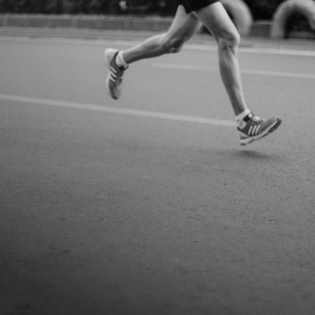 A black and white photo of a person running on a street.