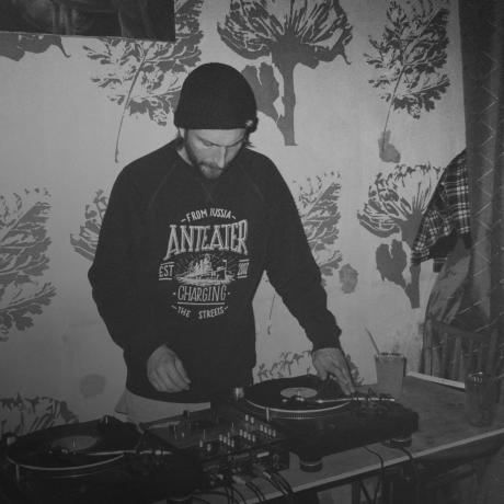A man djing on a turntable in front of a wall.