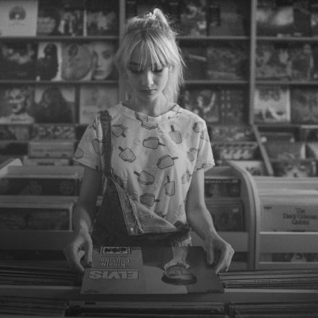 A black and white photo of a woman in a record store.