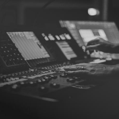 A black and white photo of a person at a mixing desk.
